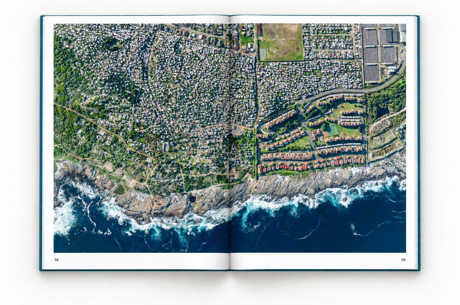 The book open at pages 58 and 59. One photograph runs across both pages: dense informal housing covers the hillside of Zwelihle down to the rocky coast, beside the ordered houses and lawns of the Hermanus Beach Club.