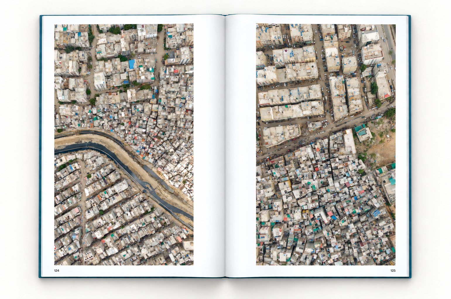 The book open at pages 124 and 125, one upright photograph on each page. Left: a drainage channel curves between two dense areas of low-rise housing. Right: a road separates blocks of apartment buildings from tightly packed small houses.