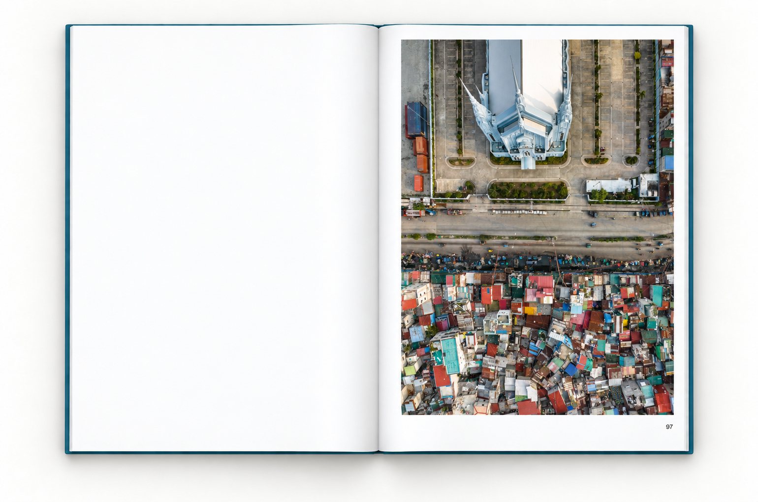 The book open at page 97, the left page blank. A pale blue church with spires stands in a walled compound with parking lots; across the road lies a dense area of houses with colorful roofs.