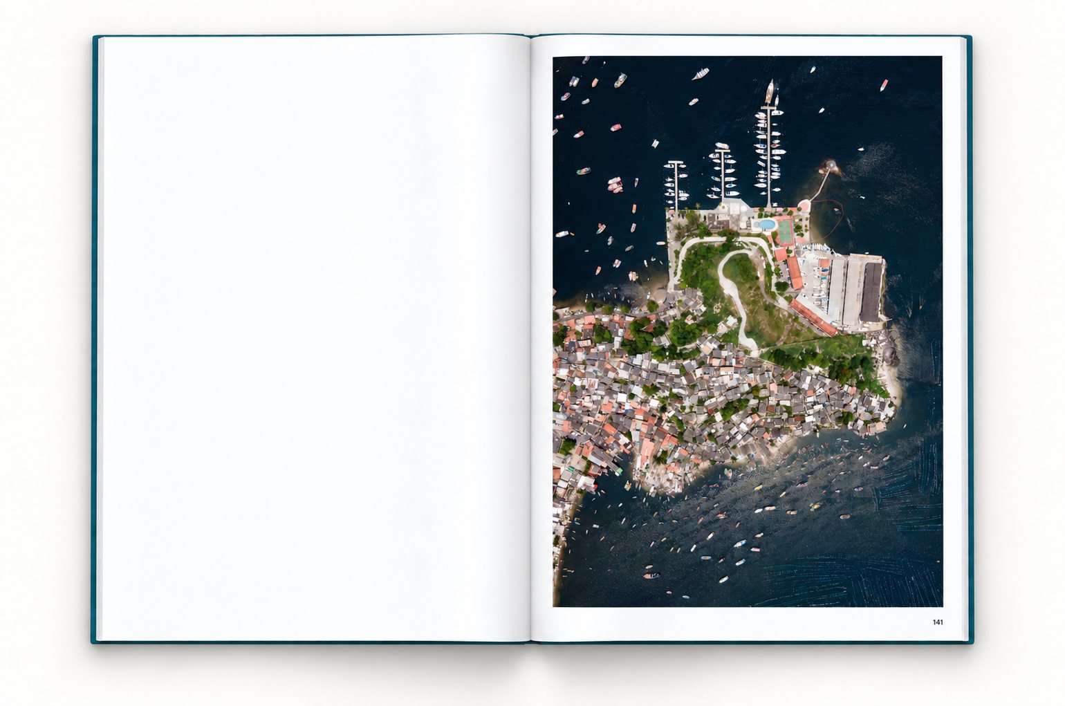 The book open at page 141, the left page blank. A yacht club with piers, a pool and sports courts sits at the tip of a peninsula; behind it, small houses cover the shore, and fishing boats lie in the bay.