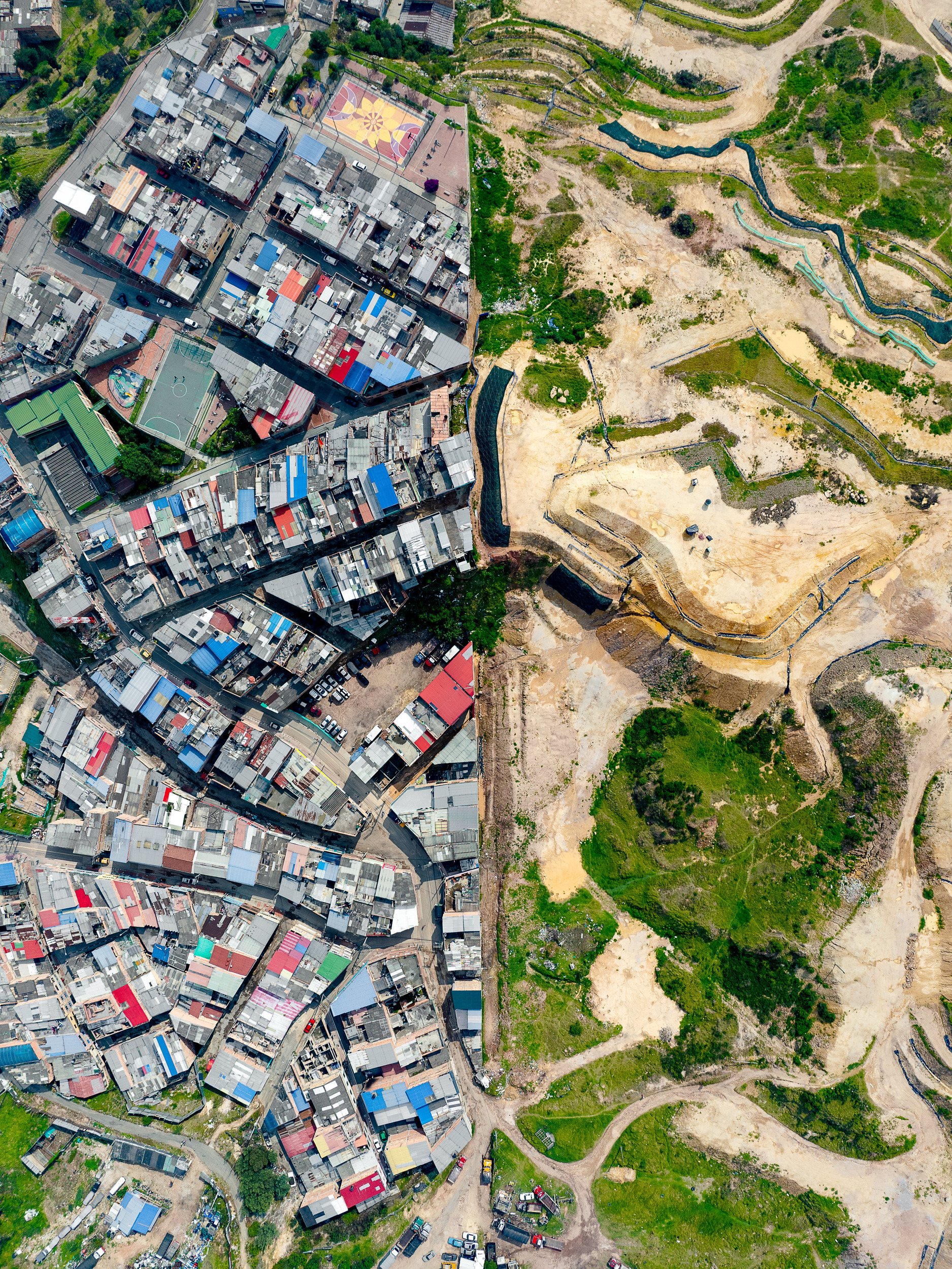 Aerial photograph of Arboleda Sur, a hillside neighborhood in Bogotá, next to open ground under construction.