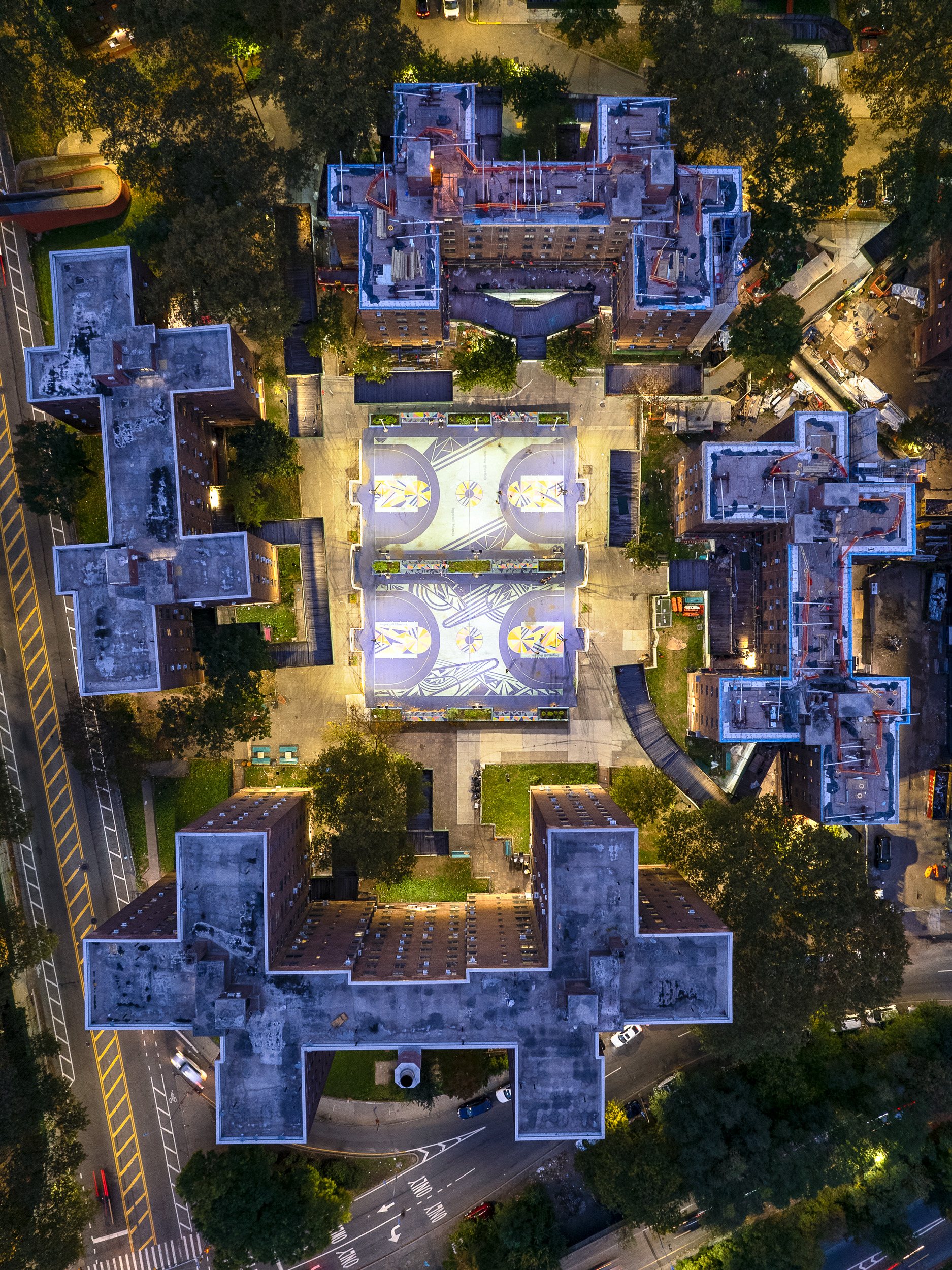 Aerial photograph of the Ingersoll Houses in Brooklyn at night, with lit basketball courts between the brick towers.