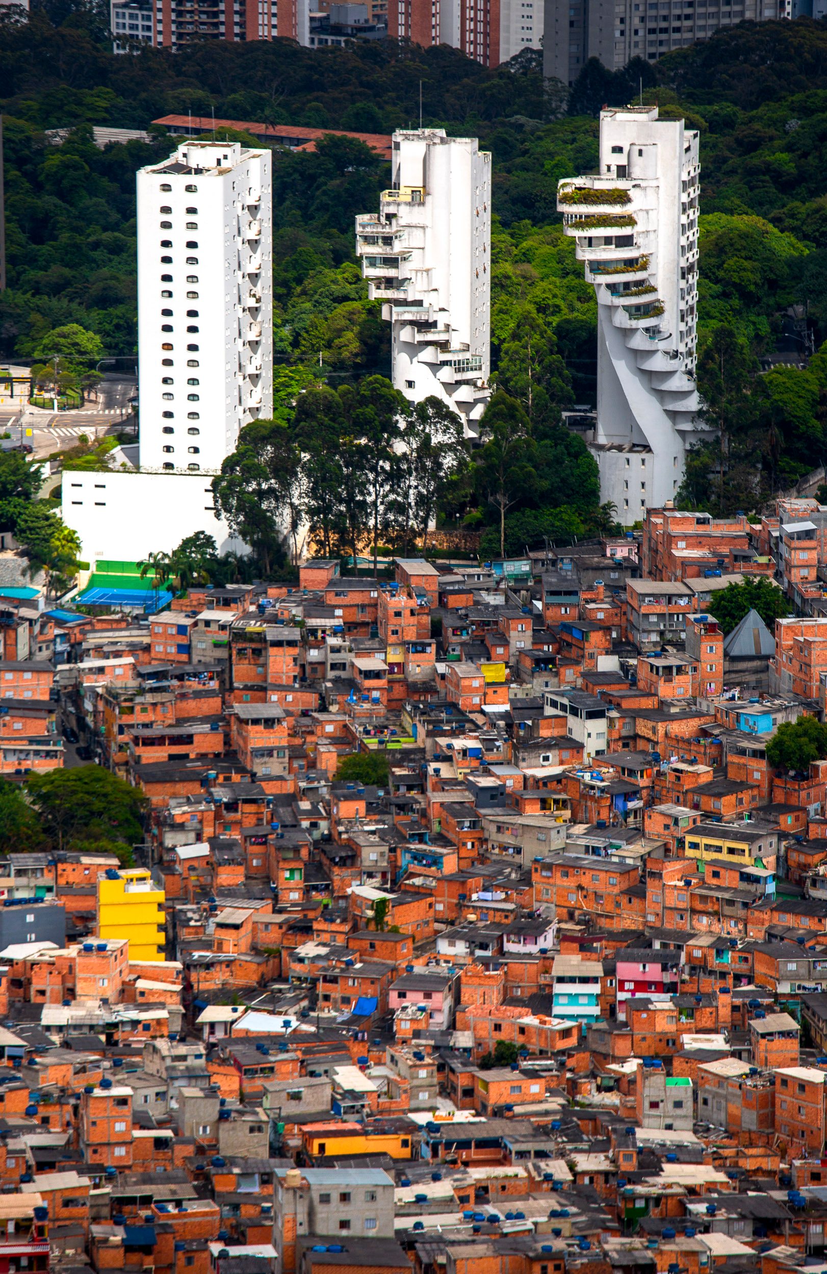 Iconic spiral-staircase apartment towers rise above the dense rooftops of São Paulo’s urban inequality.