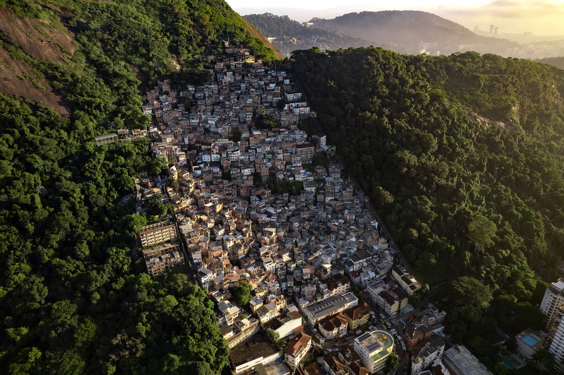 Favelas surrounding the forested peaks of Rio de Janeiro, showing the coexistence of natural beauty and inequality.