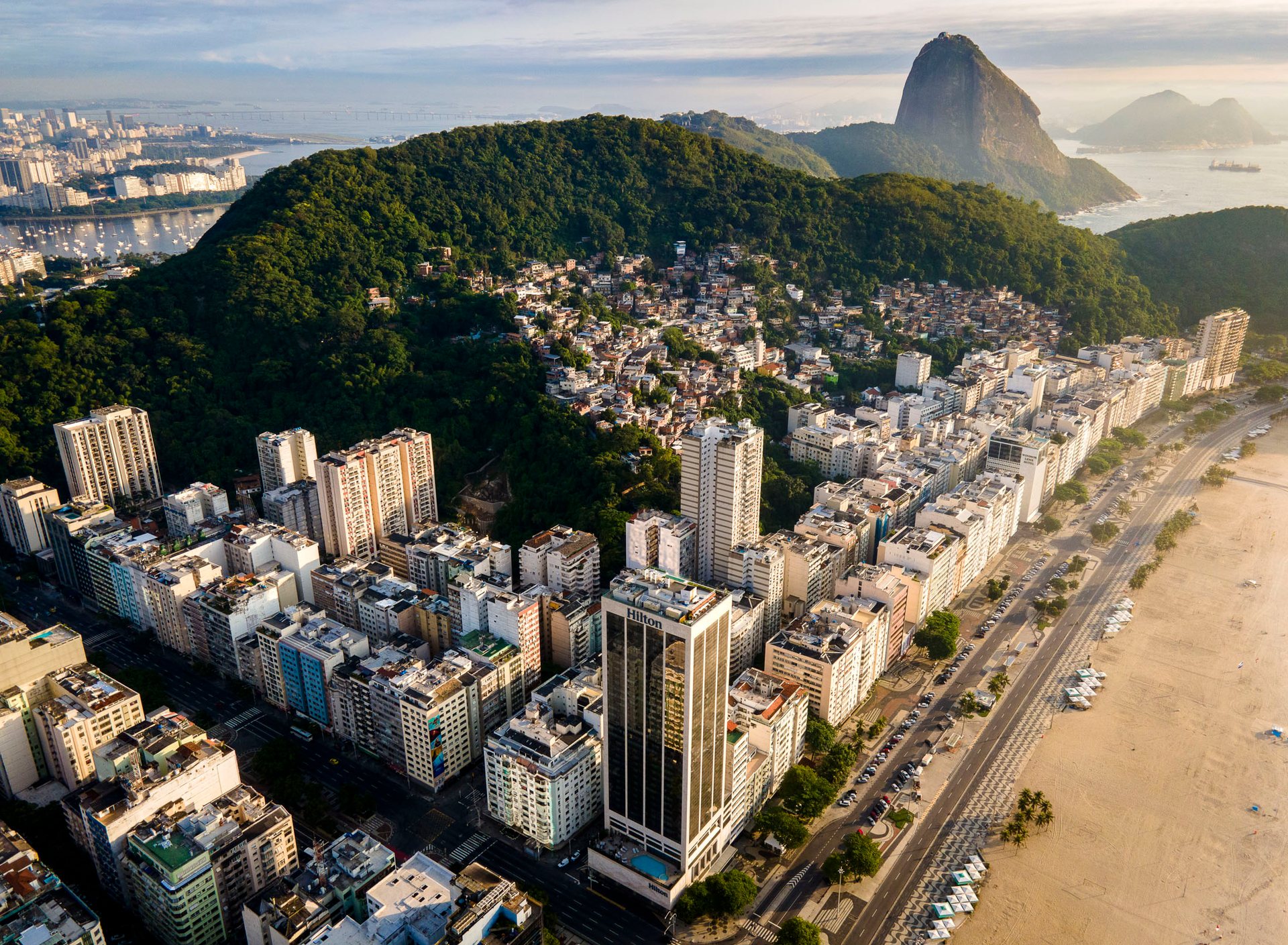 Massive concrete housing blocks rise above tightly packed blue-roofed homes in Rocinha, Rio de Janeiro.