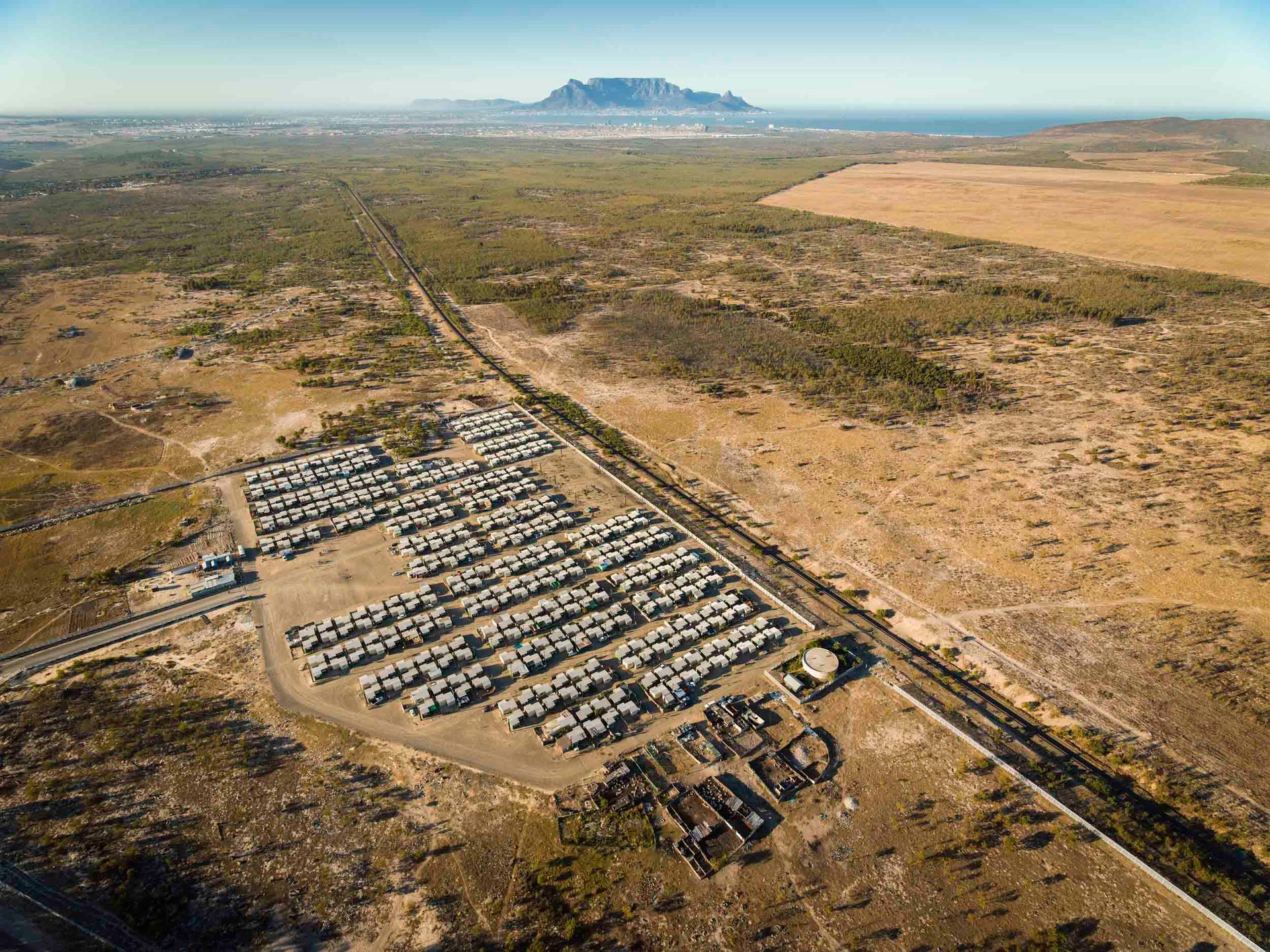 Isolated government-built housing in Cape Town, surrounded by vast dry landscape