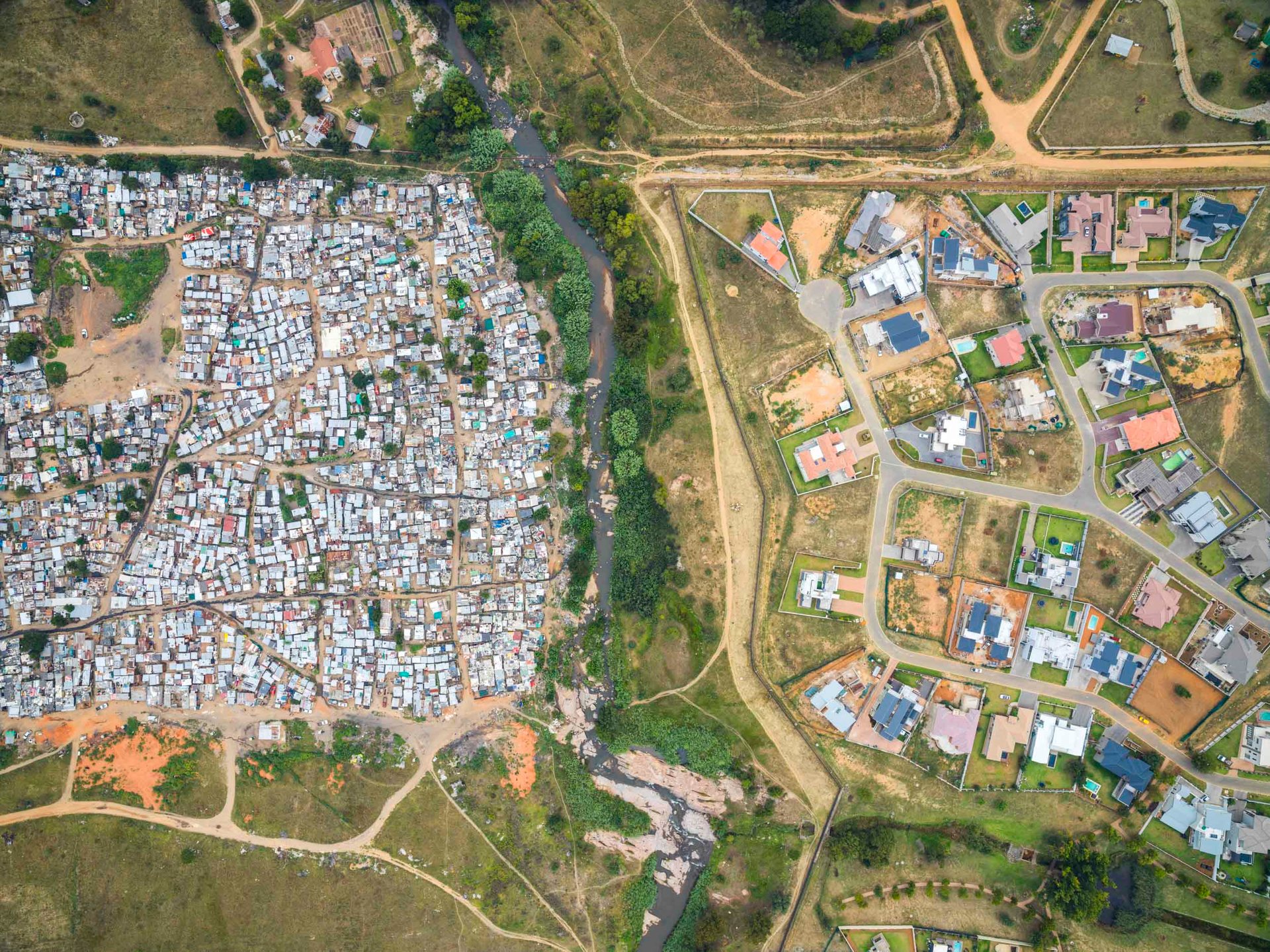 Slum and shacks opposite a river from rich homes in johannesburg south africa
